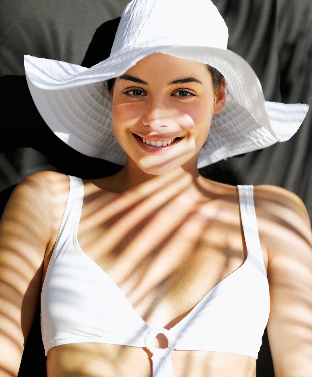 prp injections model smiling with white hat and top in dappled sunlight