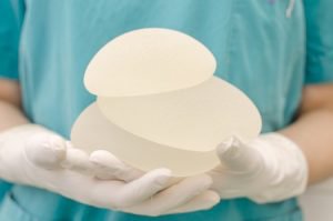 Tampa Breast Enhancement Model holding breast implants with white gloves