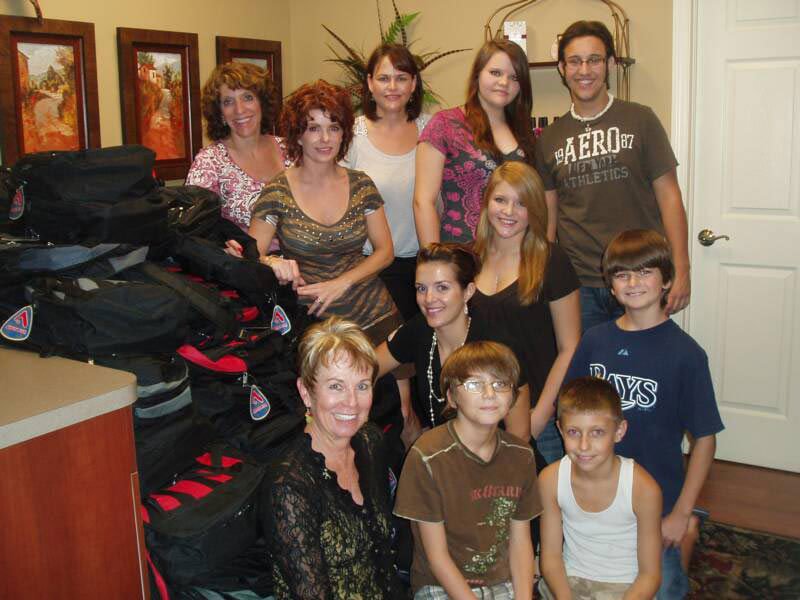 group of people posing with backpack pile