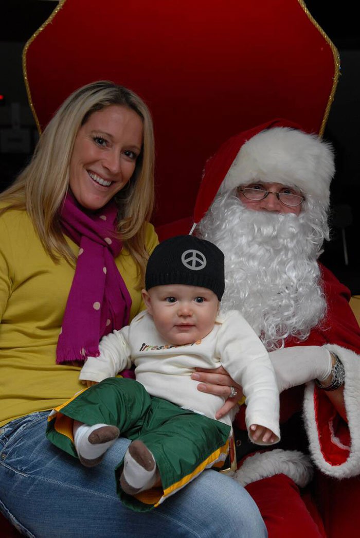 red carpet event woman and baby sitting with santa